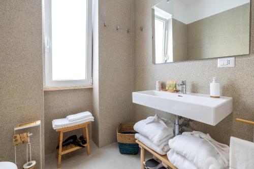 a bathroom with a sink and a mirror and towels at Villa De Nuzzo - Bed & Breakfast in Torre San Giovanni Ugento