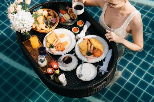 a woman sitting in a tray of food next to a pool at Sugar Marina Resort-LAGOON-Villas, Naiyang Beach in Nai Yang Beach