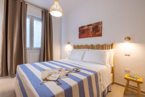 a bedroom with a bed with a blue and white striped blanket at Villa De Nuzzo - Bed & Breakfast in Torre San Giovanni Ugento