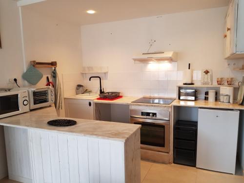 une cuisine avec des armoires blanches et un comptoir dans l'établissement l'hirondelle du coulin, à Andernos-les-Bains