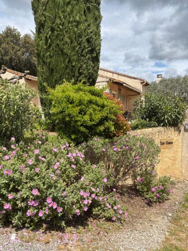 un jardin avec des fleurs roses en face d'une maison dans l'établissement LES CISTES, à Lioux