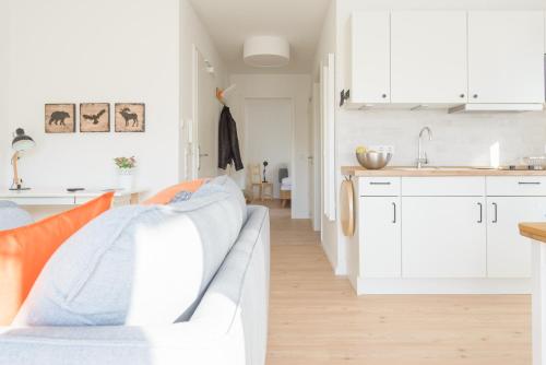 a white kitchen with white cabinets and a couch at Zweitraum in Oldenburg in Oldenburg