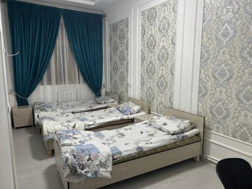3 camas en una habitación con cortinas azules en Nasrulla Samarqand Hotel, en Samarkand