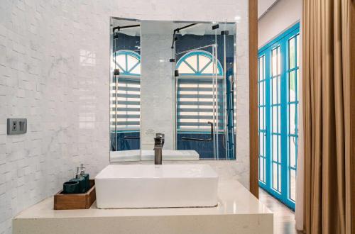 une salle de bain avec un lavabo blanc et un miroir dans l'établissement OCEAN VILLA - Sun Grand Feria Hạ Long, à Hạ Long