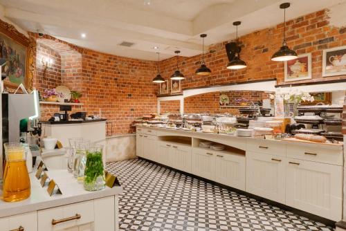 a kitchen with white cabinets and a brick wall at Hotel Diament Plaza Gliwice in Gliwice