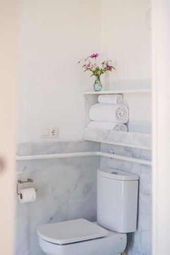 a white bathroom with a toilet and towels at Hotel A Miranda in Feás