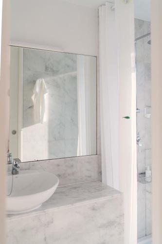 a white bathroom with a sink and a mirror at Hotel A Miranda in Feás