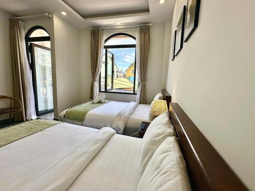 a bedroom with two beds and two windows at Amelia House - Boutique Hotel in Khu Chi Lăng