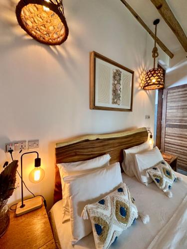 a bedroom with a bed with white sheets and pillows at Olamanga Beach Villa Adults Only in Jambiani