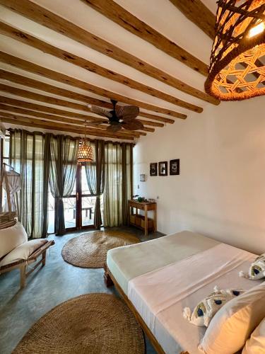 a bedroom with a large bed and a ceiling at Olamanga Beach Villa Adults Only in Jambiani