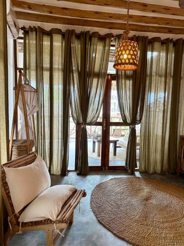a living room with a chair and a large window at Olamanga Beach Villa Adults Only in Jambiani