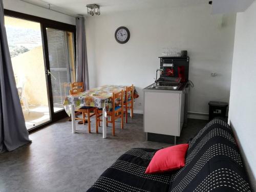 Una sala de estar con una mesa y una cocina con un reloj. en T2 log entier Porticcio 35m piscine-mer-resto 400m, en Grosseto-Prugna