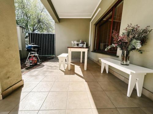 eine Veranda mit zwei weißen Bänken und einem Fenster in der Unterkunft Dottie's charming cottage two bedroom apartment and workspace in Paarl