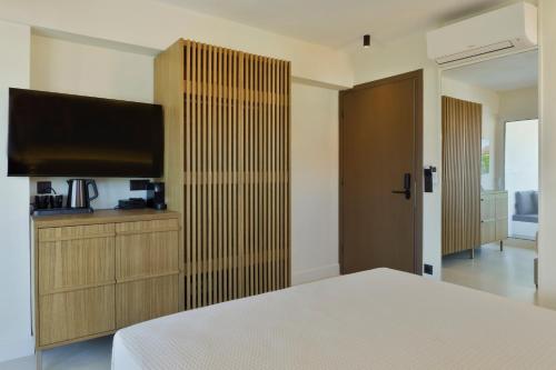a bedroom with a bed and a flat screen tv at Palm Boutique Suites in Pefkohori