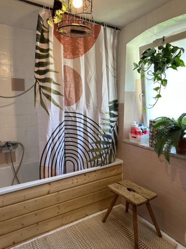 a bathroom with a tub with a shower curtain and a bench at Zimmer in rustikalem alten Haus in Tiefenpölz