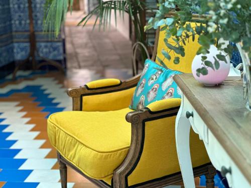 a table with two yellow chairs and a vase on it at Hostal Casa Alborada in Conil de la Frontera