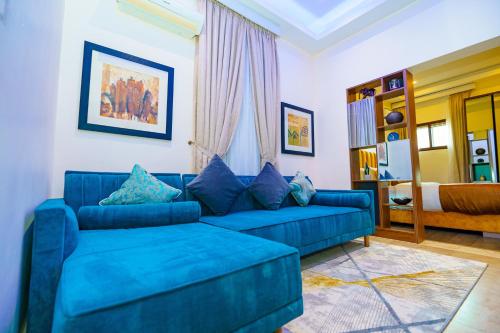 a living room with a blue couch and a bed at Qlets Privé in Abuja