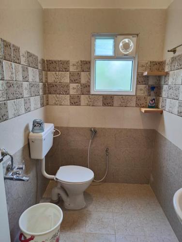 a bathroom with a toilet and a sink and a window at Parthos Chalet in Ibrāhīmpatan