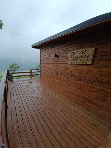 a building with a wooden deck with a sign on it at Sherpa Pihenőház in Nagymaros