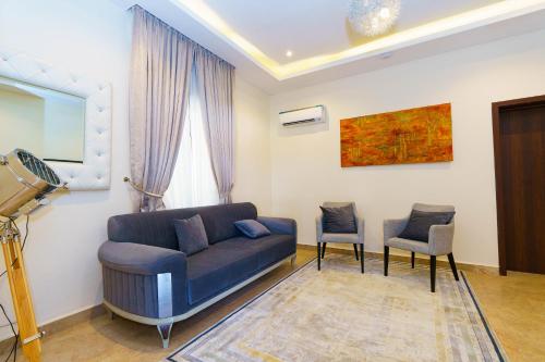 a living room with a blue couch and two chairs at Qlets Privé in Abuja