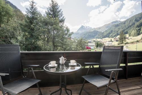 a table and two chairs on a balcony with mountains at Haus Gariella in Gargellen