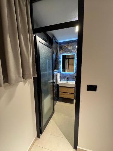 a bathroom with a glass door leading to a sink at Cozy Double Room in City Center in Shkodër