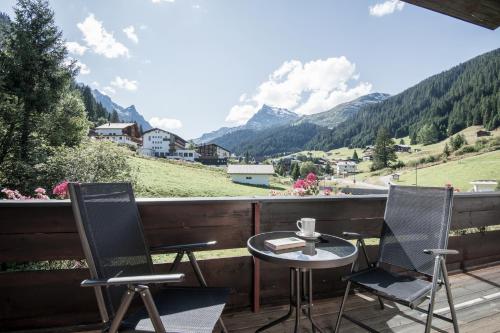 a table and two chairs on a balcony with mountains at Haus Gariella in Gargellen