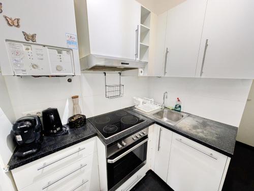 cocina pequeña con armarios blancos y fogones horno superior en Lovely 2BR Apartment in Praterstern Area, en Viena