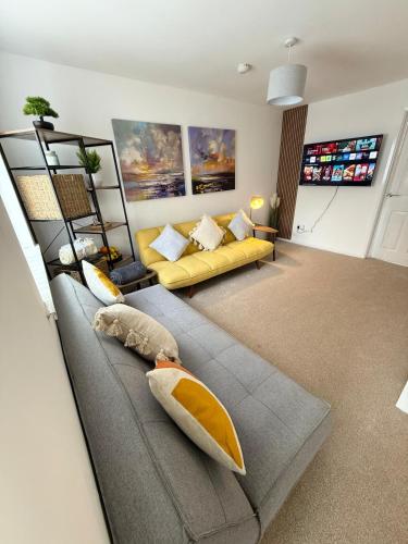 a living room with a couch and a yellow sofa at Lovely 2 Bed End Terrace - Private Parking - Garden in Cardiff