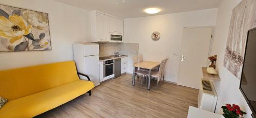a living room with a yellow couch and a kitchen at Cina Apartments in Cavtat
