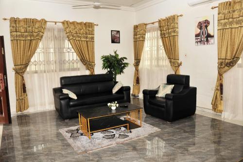 a living room with a black couch and two chairs at Luxury Spacious Apartment in Kumasi