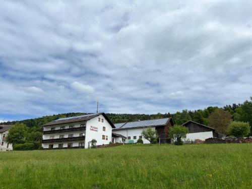 a building in a field next to a grassy field at Pension Jodlbauer in Schöllnach