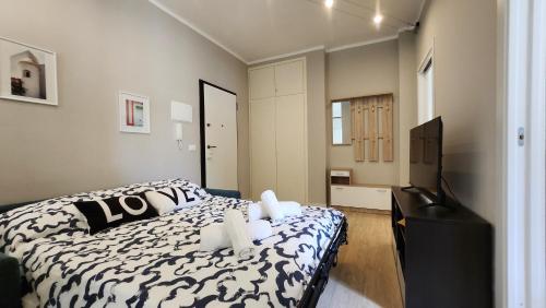 una camera con un letto bianco e nero e una TV di 200m from the sea, New flat with AC and WiFi a Loano