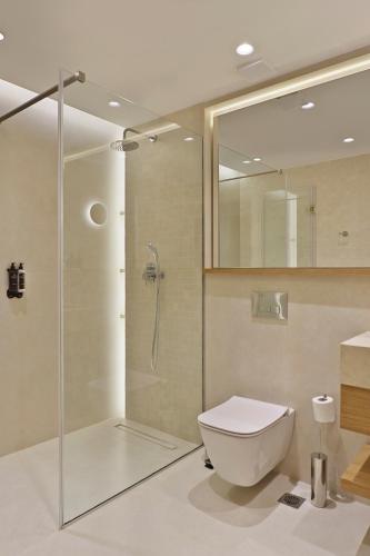 a bathroom with a toilet and a glass shower at Palm Boutique Suites in Pefkohori