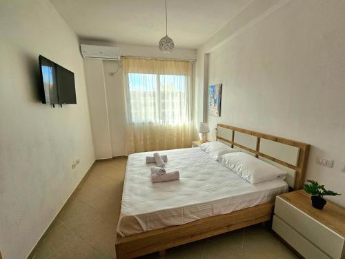 a bedroom with a large bed with a tv on the wall at Vlora Beach Apartment Orikum in Orikum