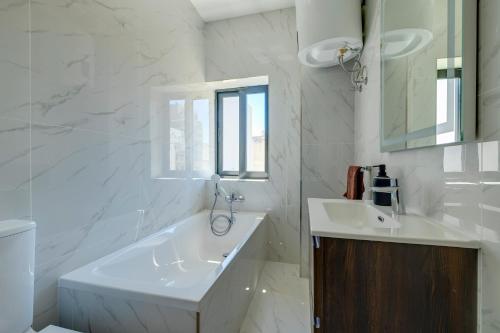 Un baño blanco con bañera y lavabo. en Cozy 2BR Sliema Getaway by the Water, en Sliema