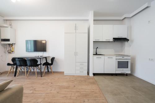 Una cocina con gabinetes blancos y una mesa y sillas. en H Pipera Lakeview, en Voluntari