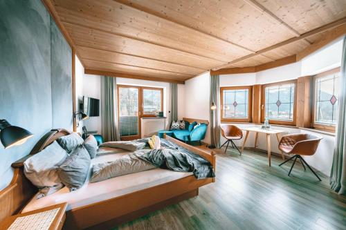 a room with a bed and a table and chairs at ALPENHOTEL TYROL - B&B - ADULTS ONLY - Alpines Lifestyle-Konzepthotel - dog friendly in Pertisau