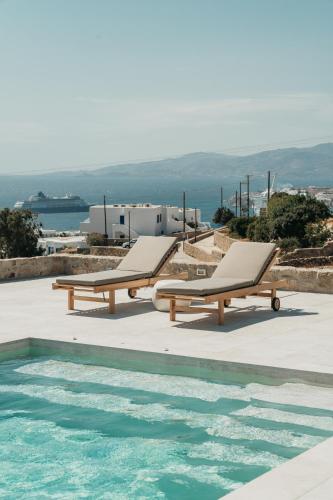 two lounge chairs are next to a swimming pool at Athera Suites Mykonos in Tagou