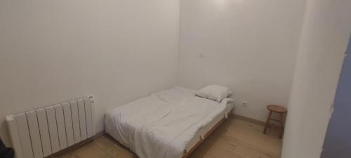 - une petite chambre blanche avec un lit et une chaise dans l'établissement Petite maison avec jardinet, à Revest-du-Bion