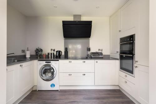 a white kitchen with a washing machine in it at Perfect for Silverstone Free Parking Stylish 2BR in Buckingham