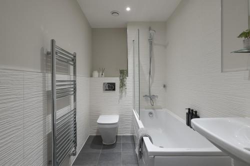 a bathroom with a tub and a toilet and a sink at Perfect for Silverstone Free Parking Stylish 2BR in Buckingham
