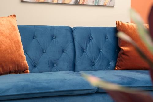 a blue couch with two orange pillows on it at Perfect for Silverstone Free Parking Stylish 2BR in Buckingham