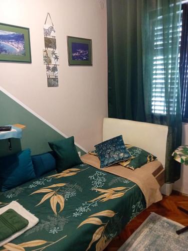 a bedroom with a bed with a green blanket and pillows at Guest House Cinderella in Herceg-Novi