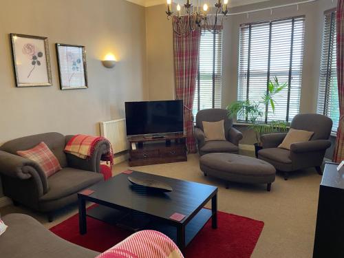 a living room with couches chairs and a television at Number 10 service apartment - Danes in Southampton