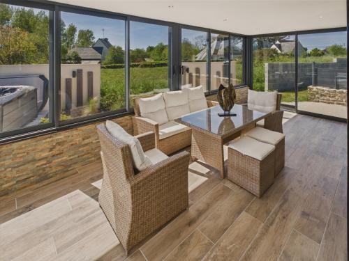 a living room with a table and chairs and windows at Piscine, jacuzzi et grande terrasse pour 7 in Penmarcʼh