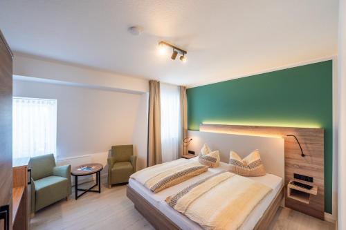 a bedroom with a bed and a green wall at Gasthaus & Pension "Zur Schaabe" in Glowe