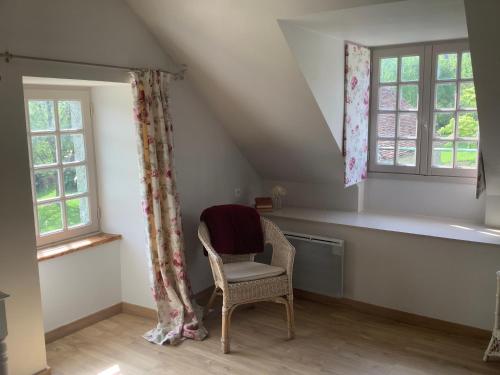 a room with a chair and two windows at Chambres d'Hôtes Belle Vallee in Domfront