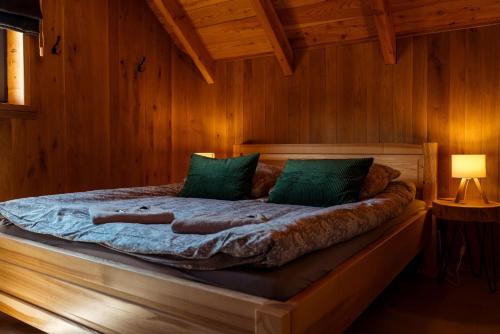 a bed with green pillows in a wooden room at Świerkowe Chatki w Koniakowie in Koniaków