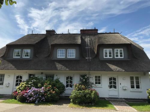 a thatched house with flowers in front of it at Hausteil Ruusenhoog in Braderup